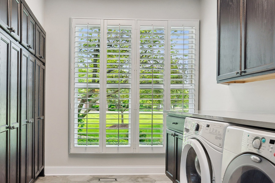 Find the perfect level of natural light for your Bakersfield laundry room with interior shutters. White Polywood shutters letting light through a laundry room window
