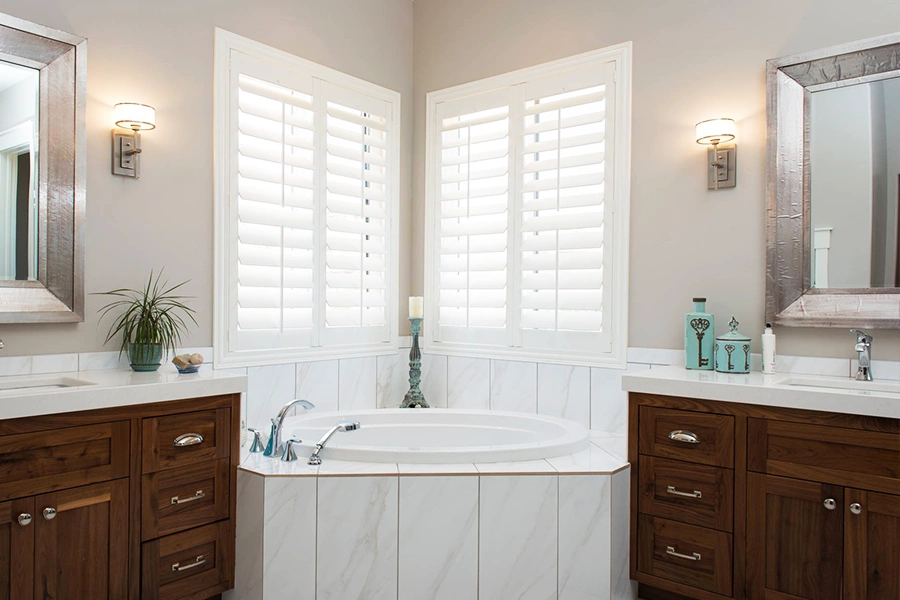 White Polywood shutters on corner windows over a bath tub