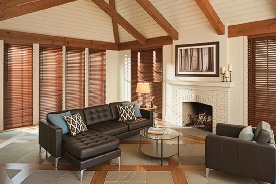 A living room with exposed wood beams, fireplace, and wood blinds on tall windows