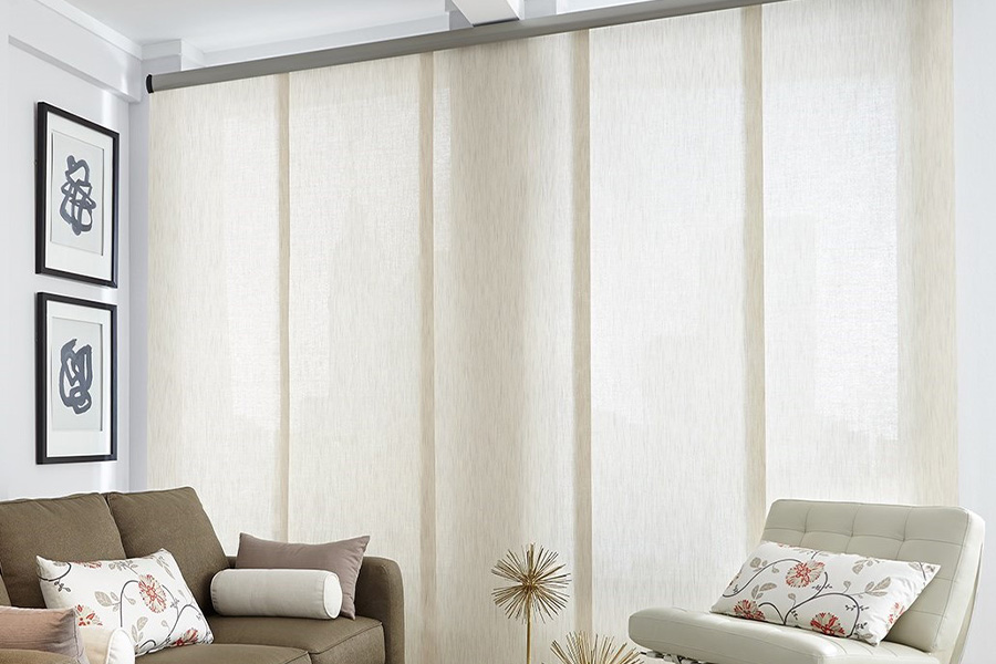 Find window treatments to complete any interior design among our extensive selection at Sunburst Shutters Bakersfield.  Long off-white window shades on a tall window in a modern living room