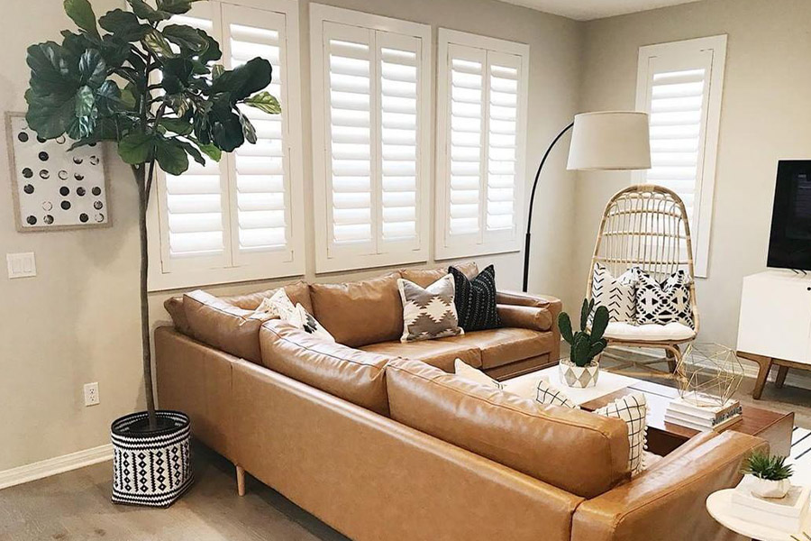 Interior shutters look effortlessly beautiful as part of any interior design. White Polywood shutters in a beige and brown living room