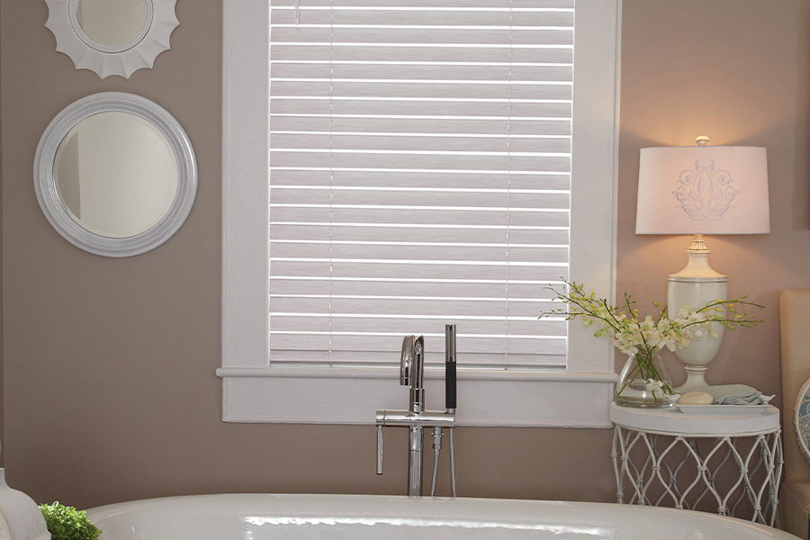 Faux-wood blinds come in both corded and cordless styles. white faux wood blinds over bathtub