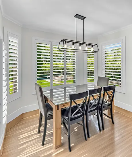 bay windows with white polywood shutters within a breakfast nook with table and chairs