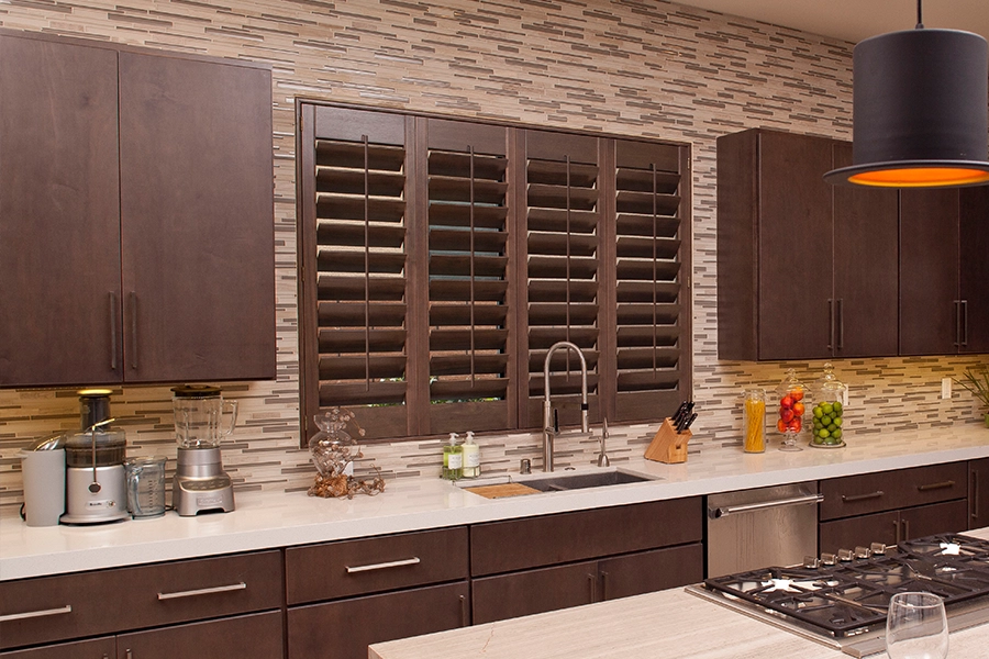 Brown wood shutters on a kitchen sink window