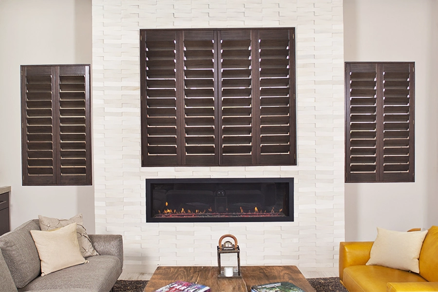 Wood Ovation® shutters in a living room with white walls and a fireplace