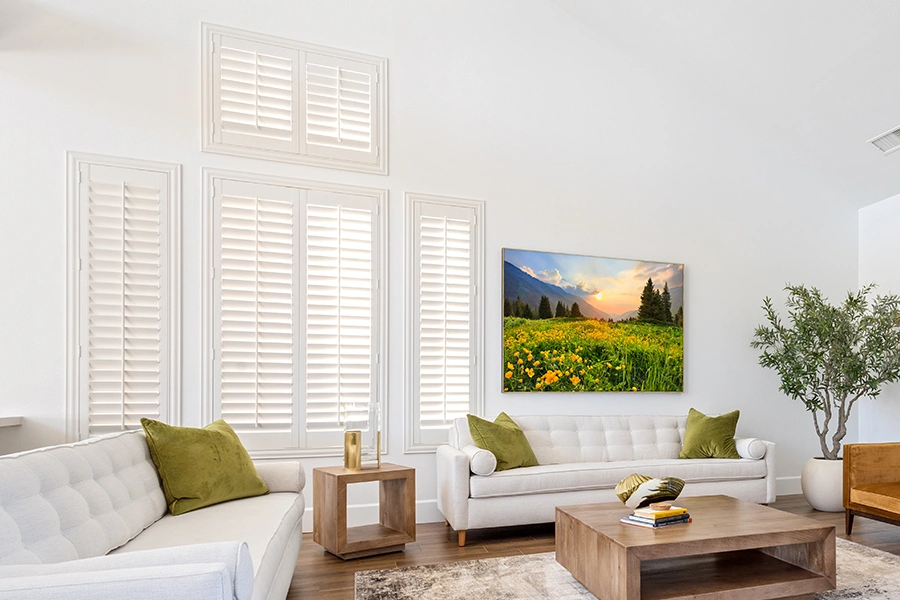 White Polywood shutters on different sizes of windows in a white living room