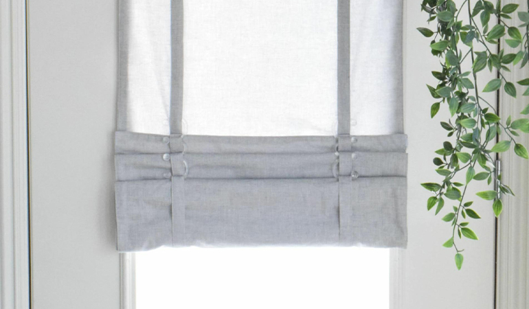 With a tiered tumble shade in Bakersfield, you can block sun glare all year round. Gray rolled tumble shade on a glass door