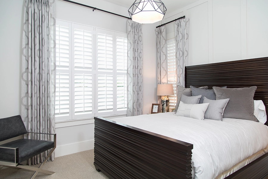 Mismatched bedroom windows with Polywood shutters and patterned curtains